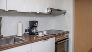 Una cocina con cafetera, lavamanos y estufa.