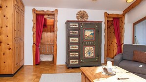 Una habitación acogedora con paredes de madera, un sofá, un armario con paneles decorativos y una pequeña mesa con una vela.