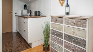Una cocina con cafetera, hervidor y una botella de vino sobre la encimera.