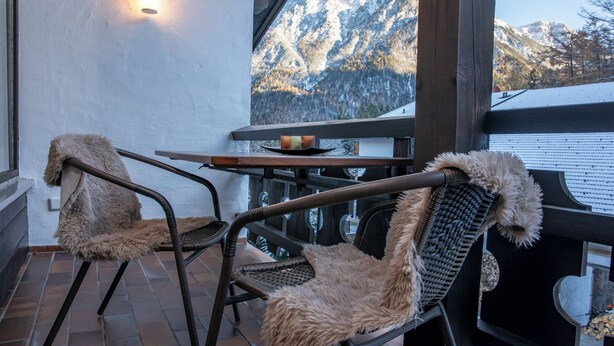 Un patio con dos sillas, una mesa y una luz instalada en la pared.