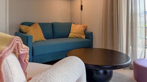 Una sala de estar moderna con un sofá azul, una mesa de centro redonda y un sillón blanco.