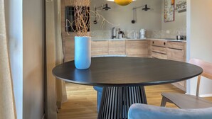 Un comedor moderno con una mesa redonda, un jarrón azul con ramas y una silla azul.