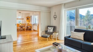 Ein Wohnzimmer mit Sofa, Couchtisch, Kamin und Blick ins Freie.