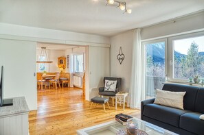 Ein Wohnzimmer mit Sofa, Couchtisch, Kamin und Blick ins Freie.