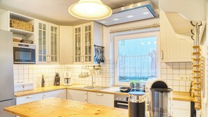 Eine moderne Küche mit weißen Schränken, einer Holz Arbeitsplatte, einem eingebauten Ofen und einem Fenster mit Blick auf einen Zaun.