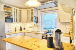 Eine moderne Küche mit weißen Schränken, einer Holz Arbeitsplatte, einem eingebauten Ofen und einem Fenster mit Blick auf einen Zaun.