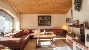 Un accogliente soggiorno con soffitto in legno, un quadro di grandi dimensioni e un camino.