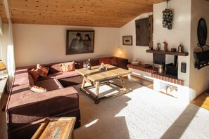 Ein gemütliches Wohnzimmer mit Holzboden, einer Couch, einem Couchtisch und einem Kamin.