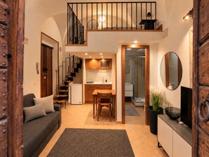 Eine kompakte Wohnung mit einer Küchenzeile, einem Essbereich, einem Wohnzimmer mit einer Couch und einer Treppe, die zu einer oberen Ebene führt.