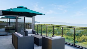 A balcony with wicker furniture, a glass enclosure, and a view of a coastal landscape. - NewVilla|Pool,Sauna,Tennis,Hoops |Rent a Private 1.2-Acre Entertainment Paradise (富津市)
