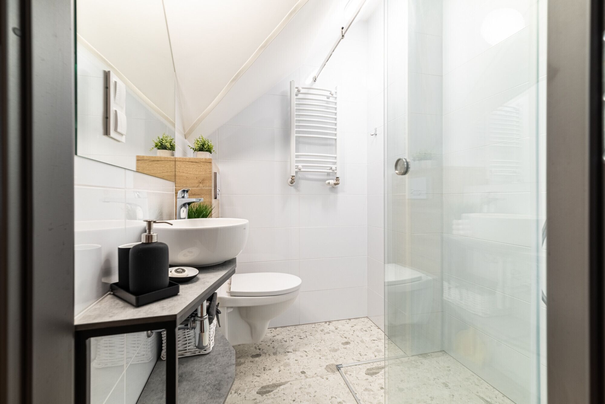 A modern bathroom with a white sink, toilet, and glass shower enclosure.