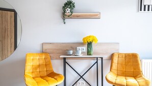 Una camera moderna con pavimento in legno, due poltrone gialle, un tavolino con un vaso di fiori e uno specchio con cornice nera.