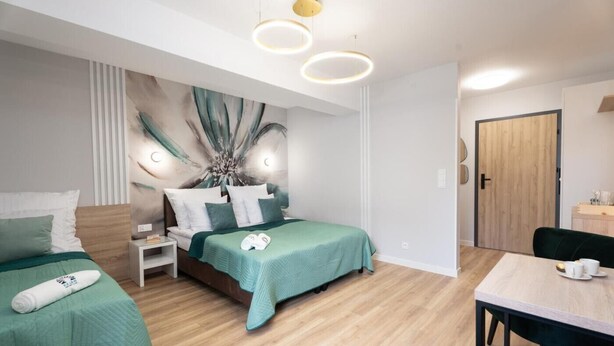 Una camera d'albergo moderna con un letto, comodini, una scrivania e una sedia.