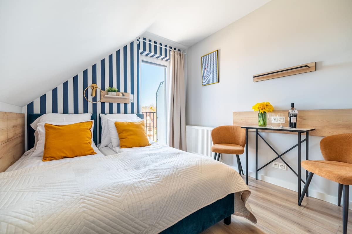 Un dormitorio con cama, escritorio, silla, ventana y radiador.
