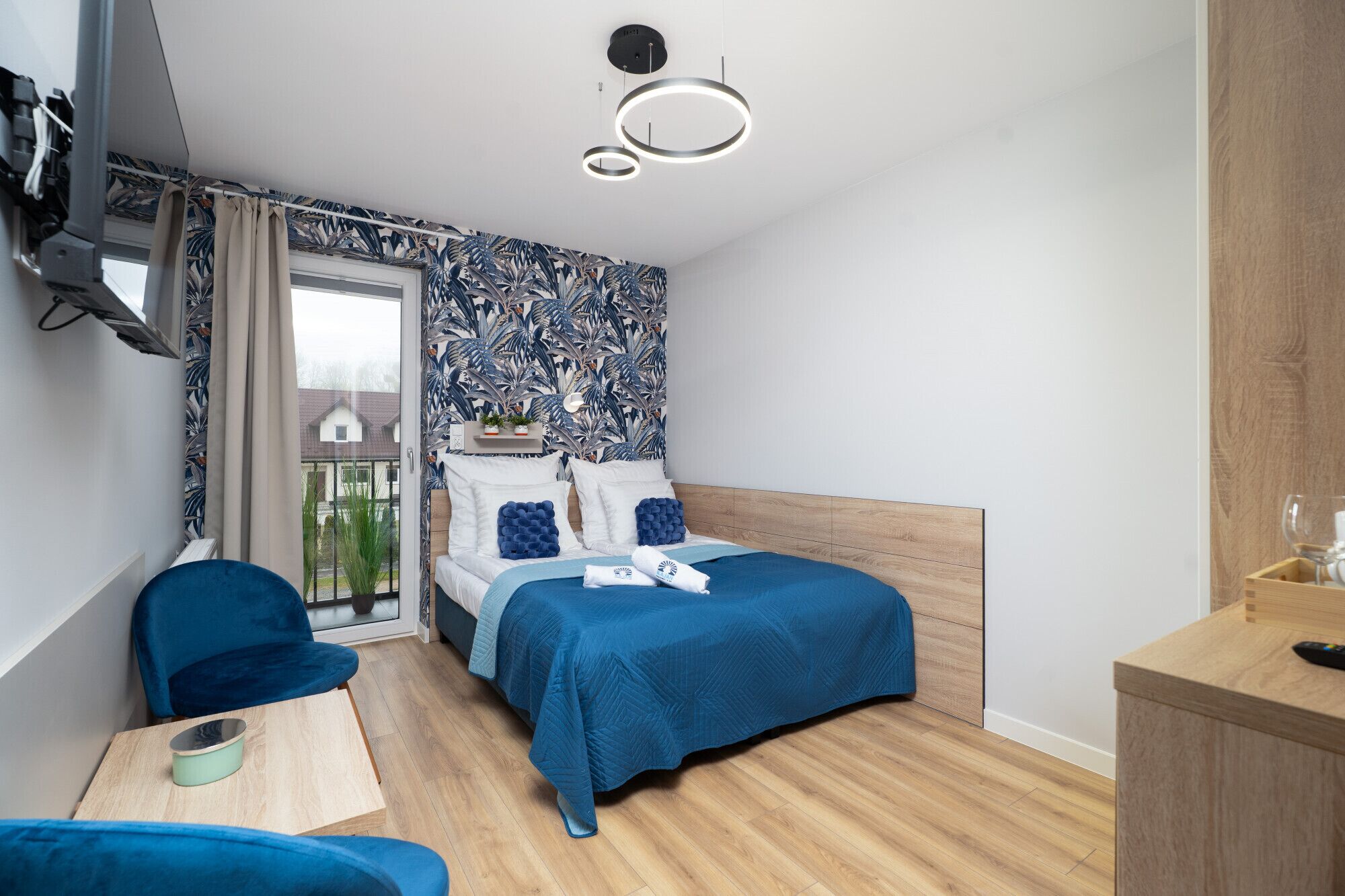 Un dormitorio con cama, escritorio, silla y vista al exterior.