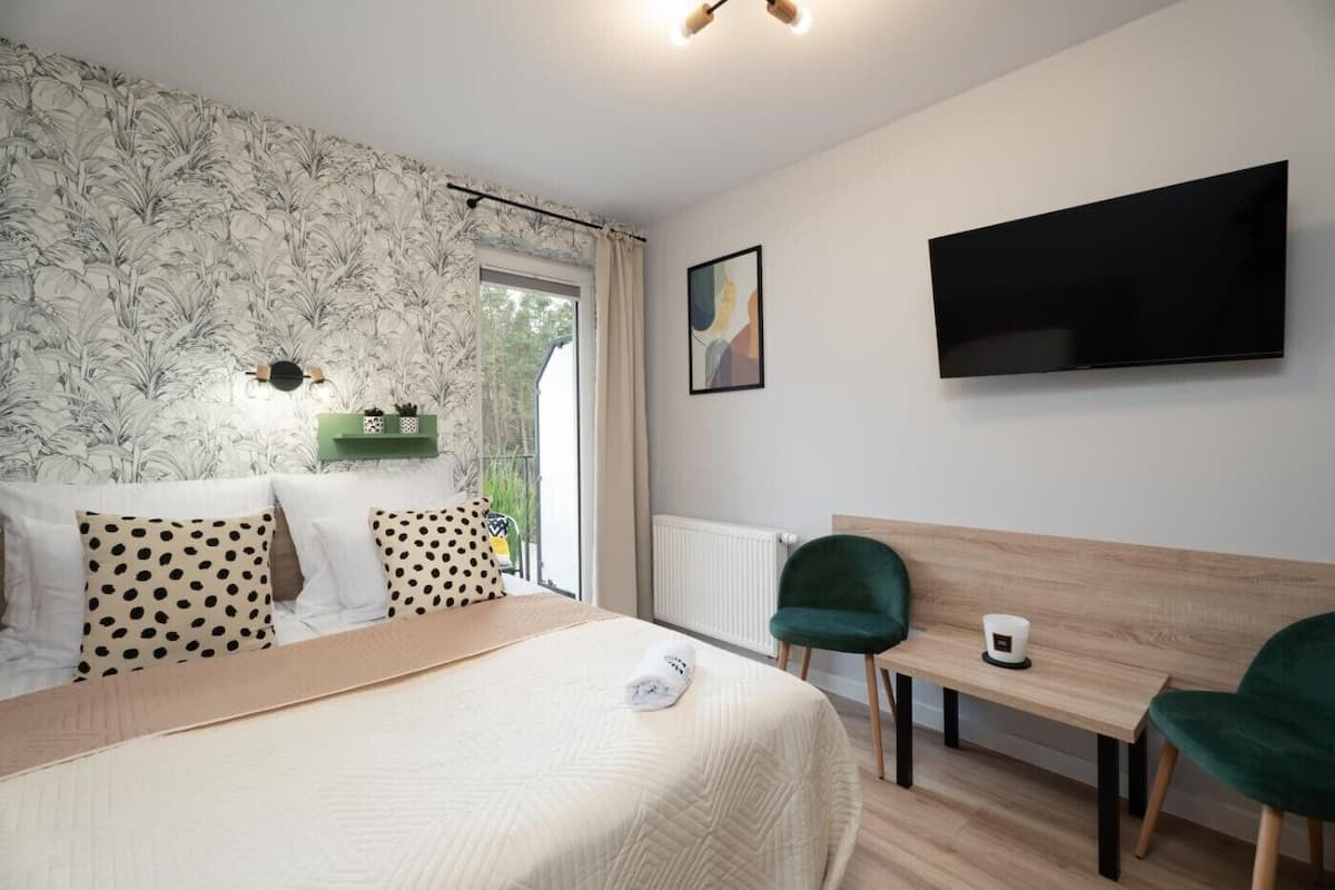 Habitación de hotel con cama, escritorio, silla, televisión y ventana con vistas.