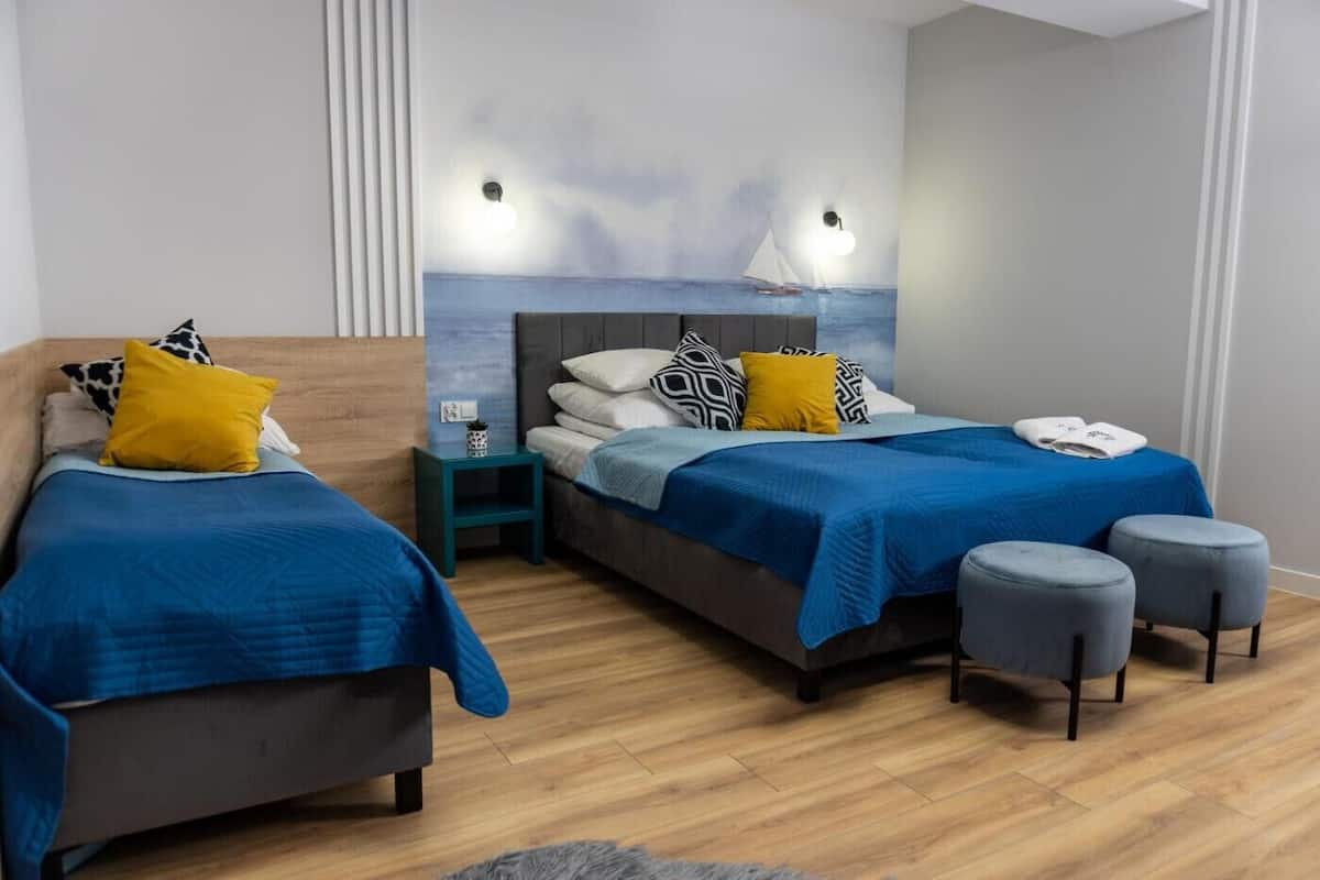 Una habitación con dos camas, una mesita de noche, una pequeña mesa y un mural en la pared.