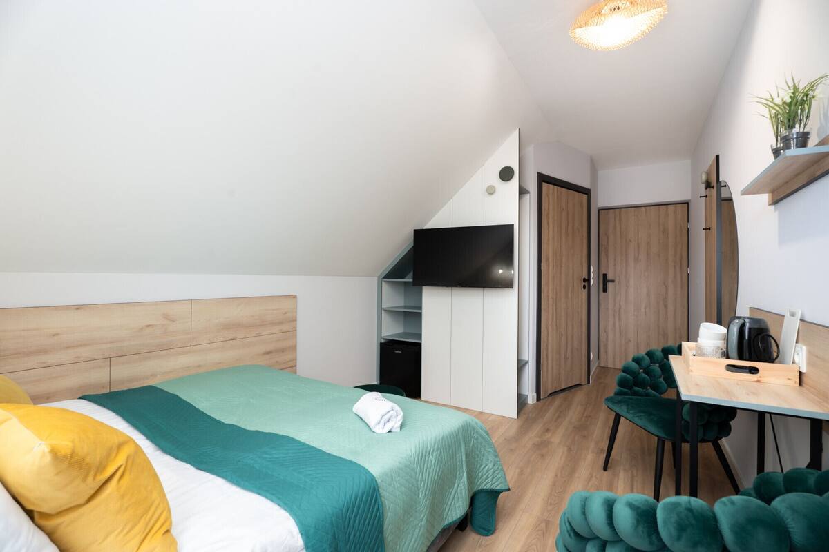 Un dormitorio con cama, escritorio, silla, televisor y armario.