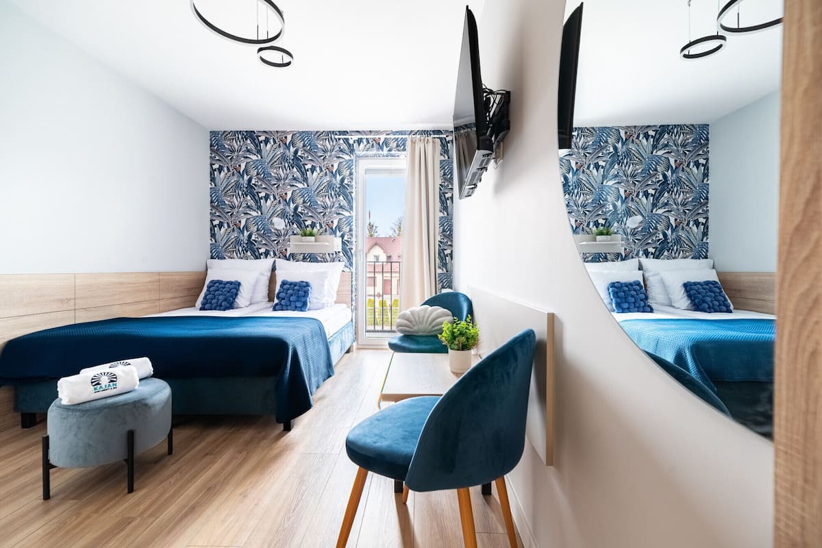 Una habitación moderna con dos camas, una mesita, una silla y un televisor montado en la pared.