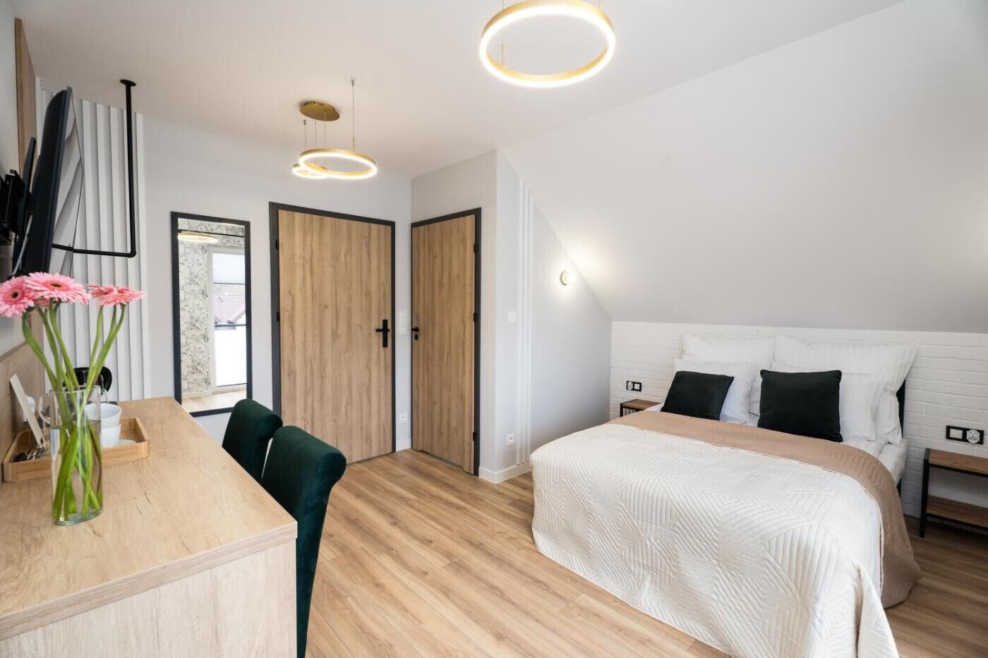 A modern bedroom with a bed, bedside tables, a desk, and a chair.