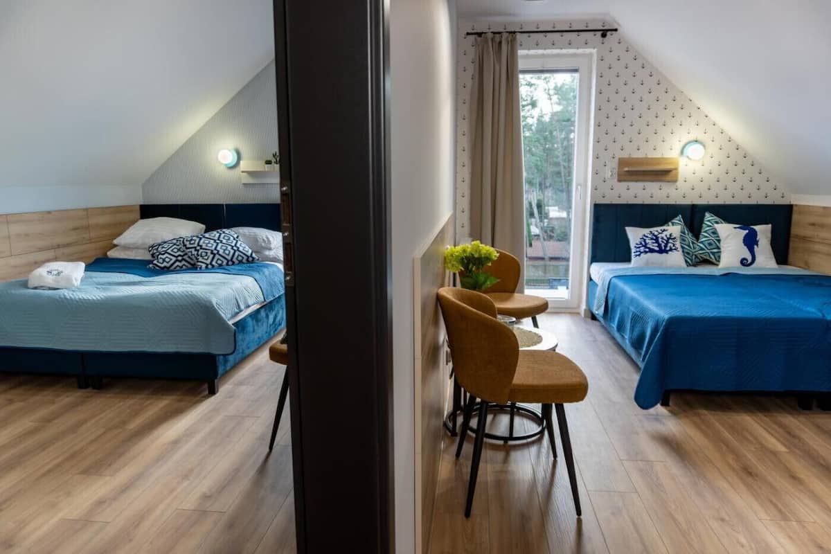 Una habitación con dos camas, una mesita con sillas y vistas al exterior.
