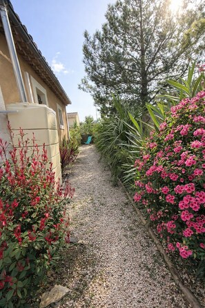A gravel pathway flanked by plants and a building with a tiled roof. - Studio 2 pers 5 min from the center of Saint Rémy de Provence, shared swimming pool (Saint-Rémy-de-Provence)