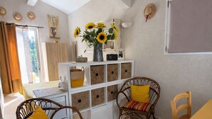 A dining area with wicker chairs, a yellow table, and a white cabinet with baskets. - Studio 2 pers 5 min from the center of Saint Rémy de Provence, shared swimming pool (Saint-Rémy-de-Provence)