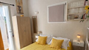 A neatly arranged bedroom with a bed, bedside tables, a wardrobe, and a window. - Studio 2 pers 5 min from the center of Saint Rémy de Provence, shared swimming pool (Saint-Rémy-de-Provence)