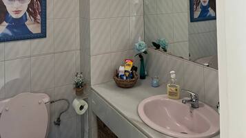 A bathroom with a toilet, sink, mirror, and tiled walls.