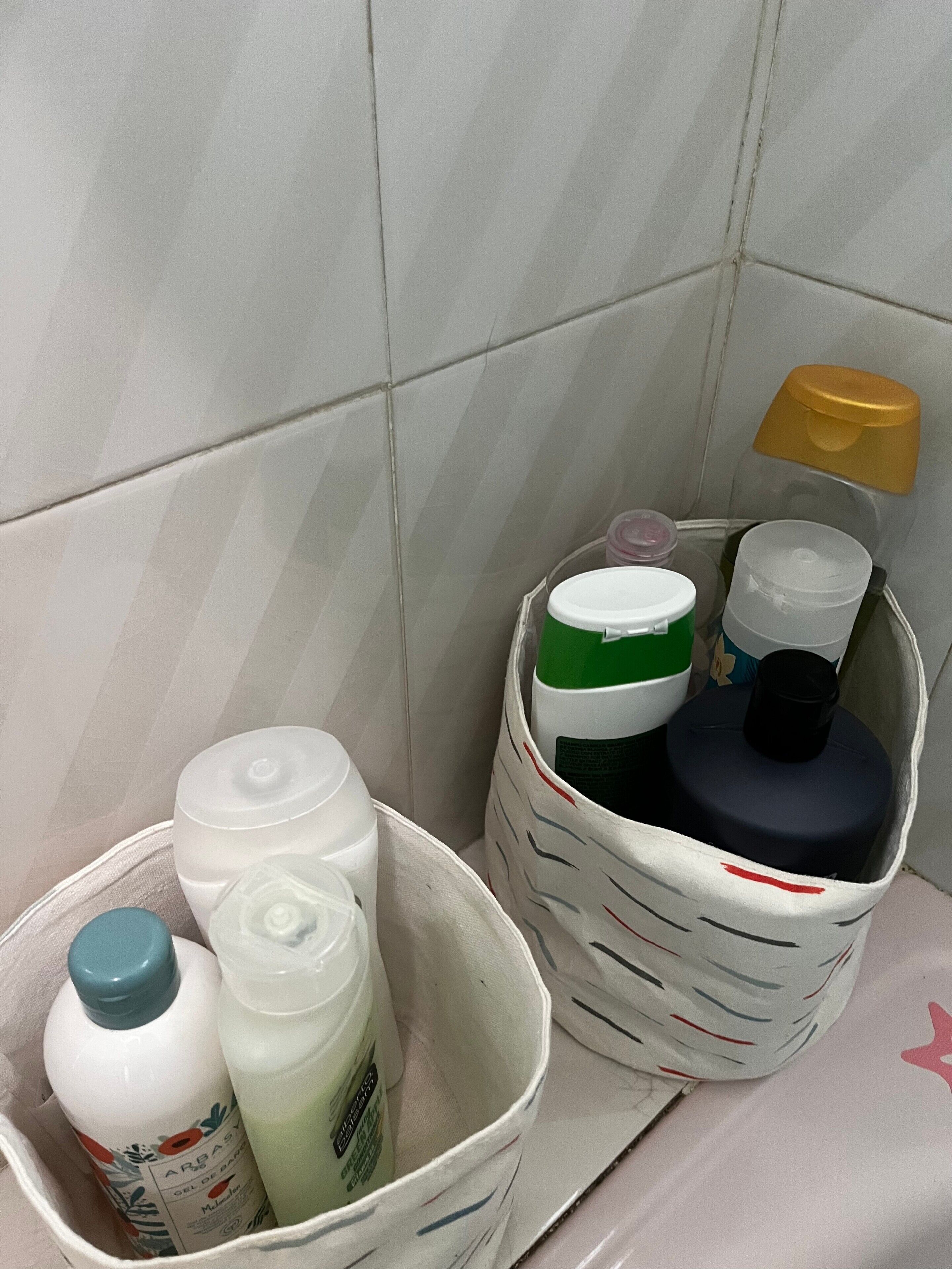 A bathroom with a white tiled wall, a white sink, and two baskets containing toiletries.