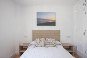 A bedroom with a bed, two bedside tables, a nightstand, a headboard, and a wall-mounted picture. - Apartment 'El Molino Del Viento' with Private Terrace, Wi-Fi and Air Conditioning (Conil de la Frontera)