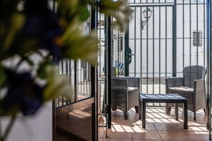 Een terras met rieten meubilair en een metalen poort.