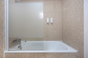A bathroom with a bathtub, a mirror, and a showerhead. - Apartment 'El Molino Del Viento' with Private Terrace, Wi-Fi and Air Conditioning (Conil de la Frontera)