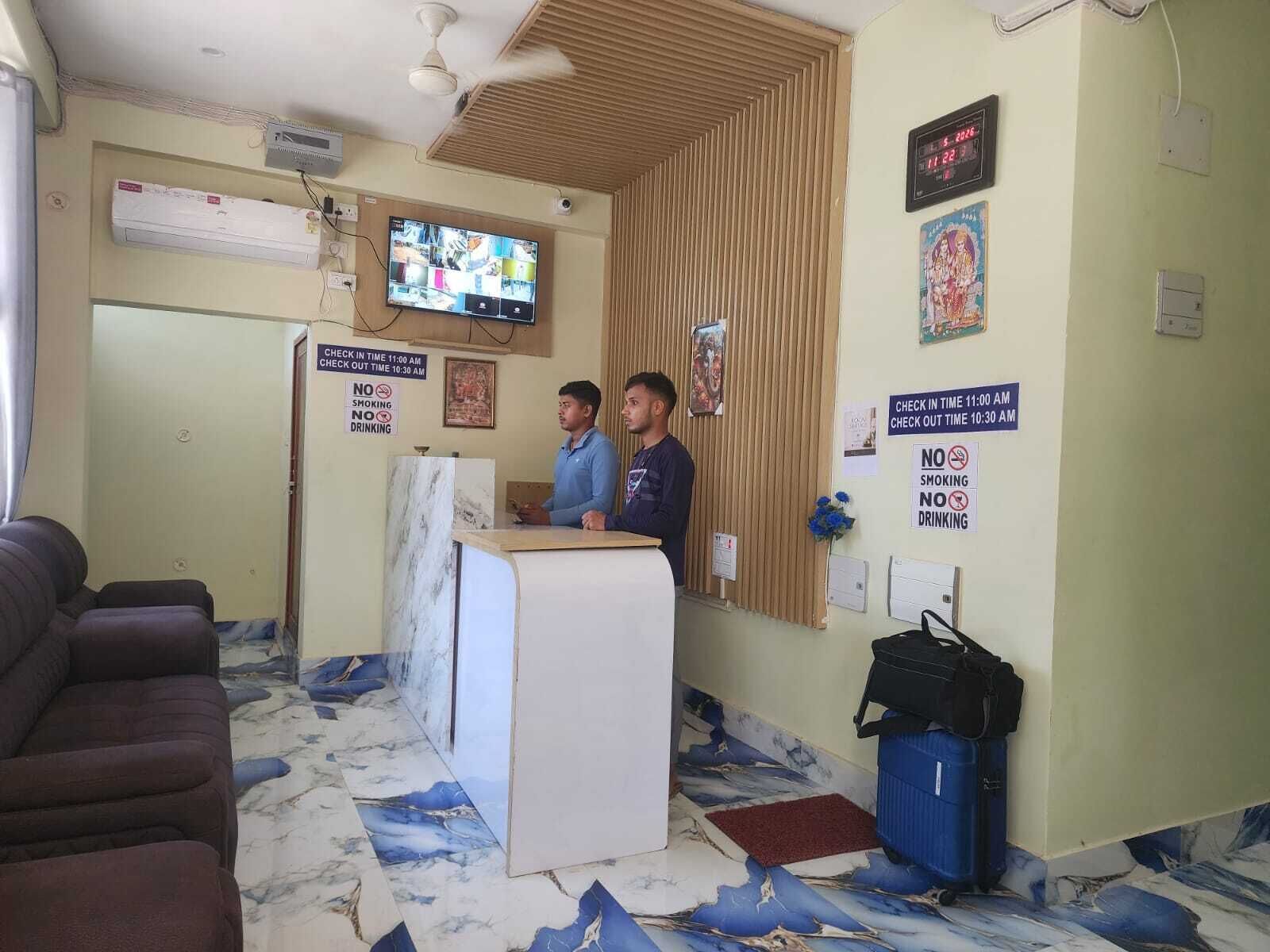 A reception area with a marble floor, a reception desk, a television, and a clock.