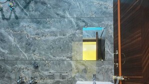 A bathroom with a marble wall, a white sink, and a shower area. - Hotel Navin Palace (Bhagalpur)