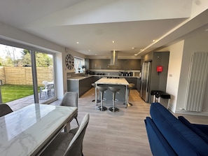A modern kitchen with a central island, bar stools, and a dining table with chairs.
