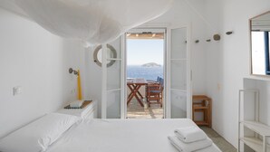 Un dormitorio con cama, escritorio y vista al mar.