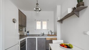 Una cocina pequeña con un lavamanos, armarios, una ventana y un frutero en la encimera.