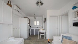 Un espacio habitable compacto con kitchenette, comedor y zona de estar con sofá y mesa.