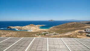 Paisaje costero con paneles solares, terreno rocoso y una isla distante.