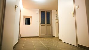 A hallway with a door, a small window, and a light fixture.