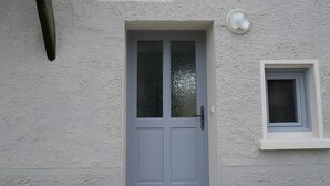 A building with a textured facade, a grey door, a small window, and a security camera.