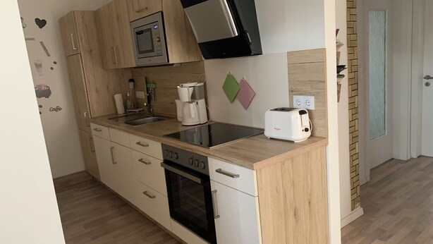 Eine moderne Küche mit Holzausstattung, einer eingebauten Mikrowelle, einer Kaffeemaschine und einem Toaster.