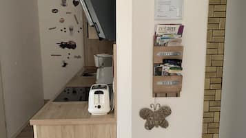 Eine kompakte Küche mit Toaster, Kaffeemaschine und einer an der Wand befestigten Ablage mit Aufbewahrungsboxen.