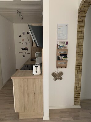 Eine kompakte Küche mit Toaster, Kaffeemaschine und einer an der Wand befestigten Ablage mit Aufbewahrungsboxen.