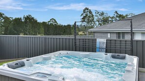 A hot tub with a metal fence and a house in the background. - Hunter Hideaway | Pet Friendly, Games Room, Spa (Cessnock)
