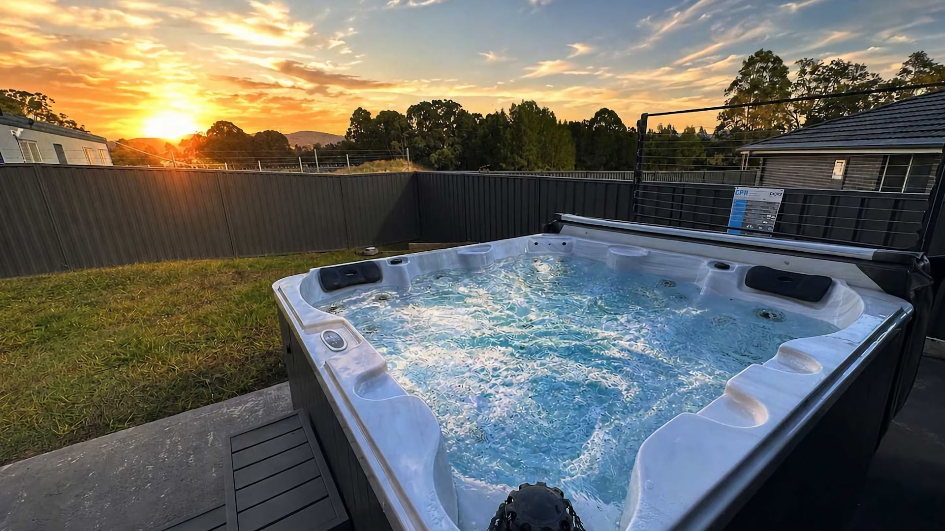 Un bain à remous avec une terrasse en bois et une vue sur le coucher de soleil.