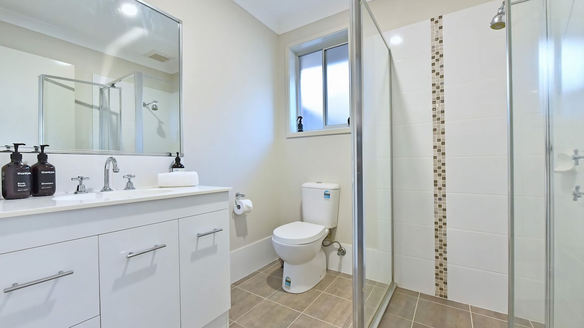 Une salle de bain avec une douche à parois de verre, des toilettes et un lavabo avec un miroir au-dessus.
