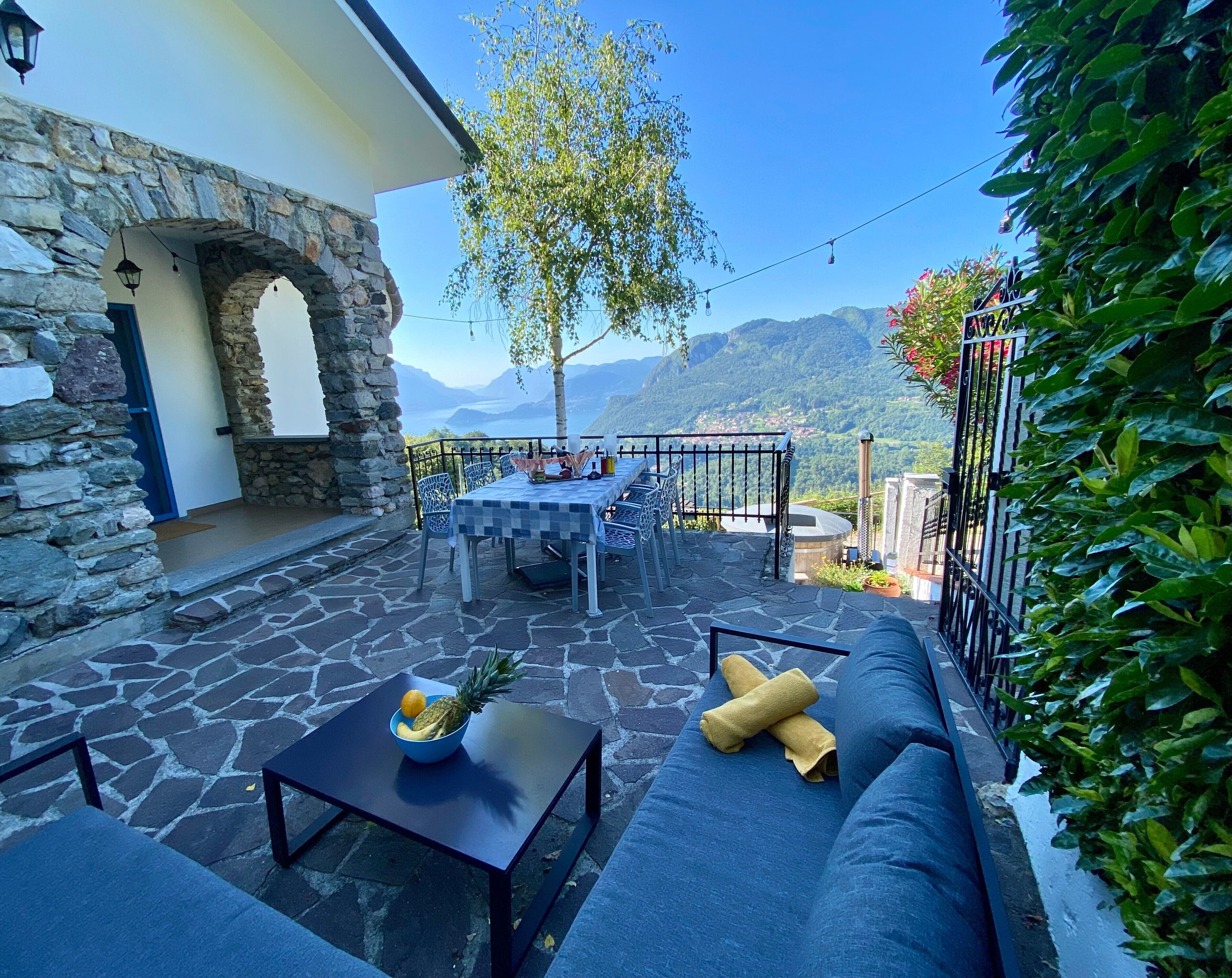 A stone patio with a table, chairs, and a sofa.