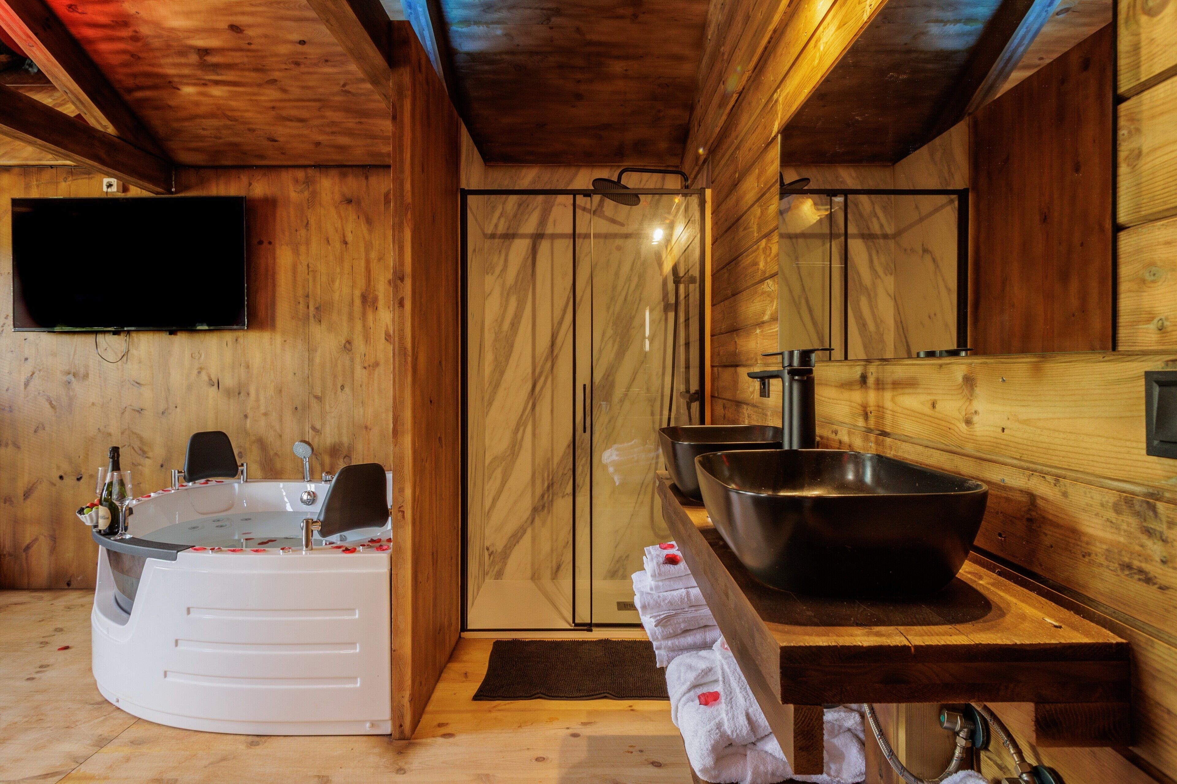 Een houten interieur met een bubbelbad, een grote spiegel en een wastafel.